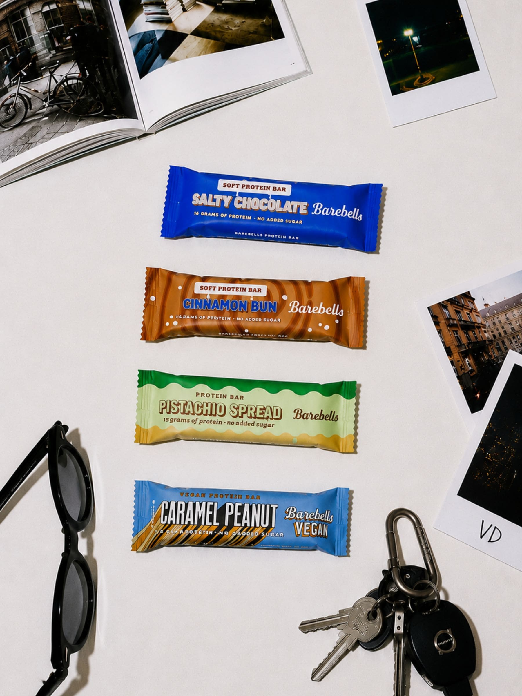 Barebells protein bars on a table with photos and sunglasses