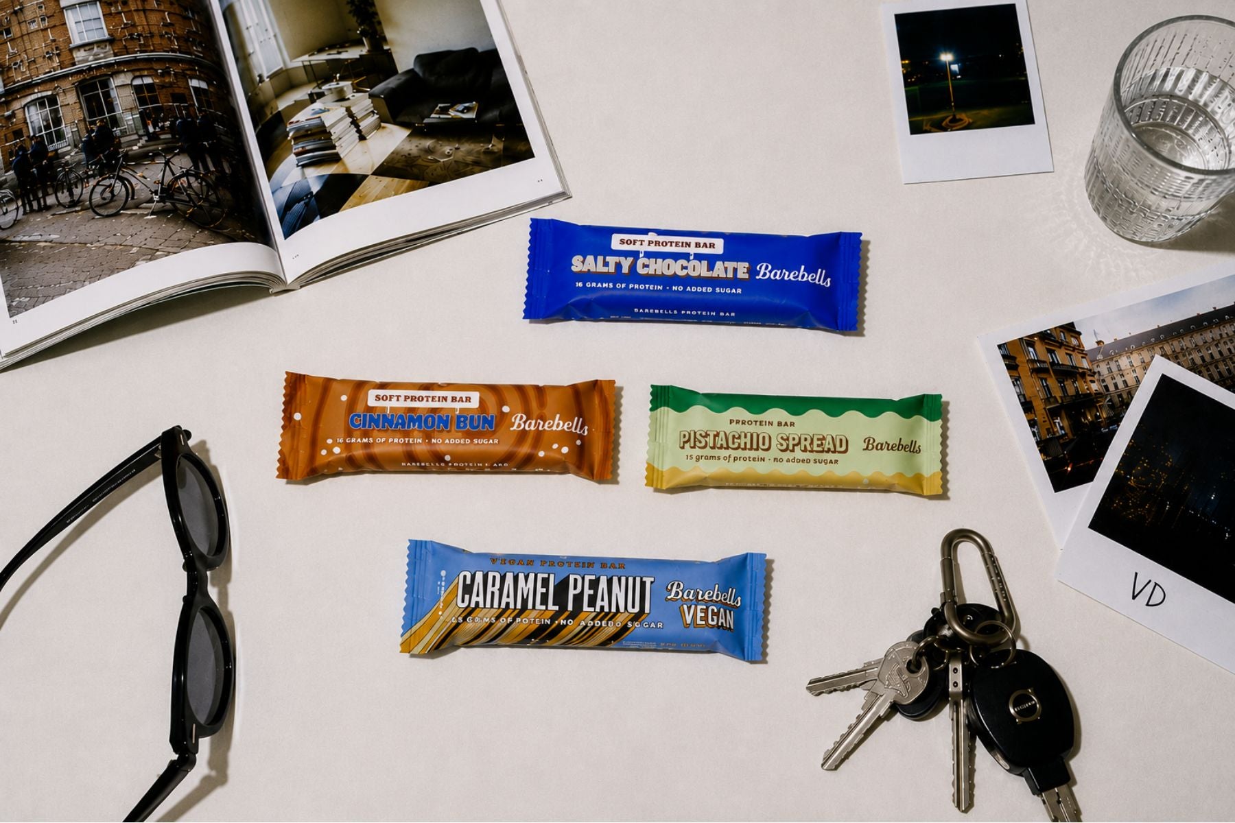 Barebells protein bars on a table with photos and sunglasses