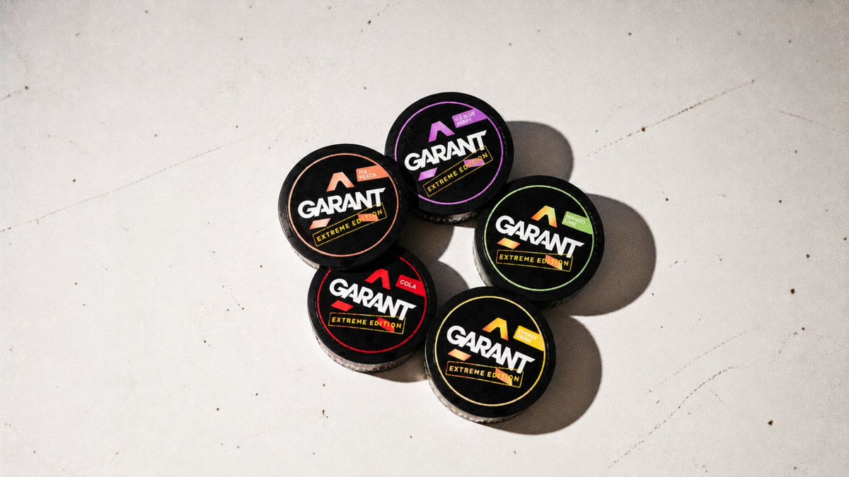 Five cans of Garant Nicotine Pouches on white surface