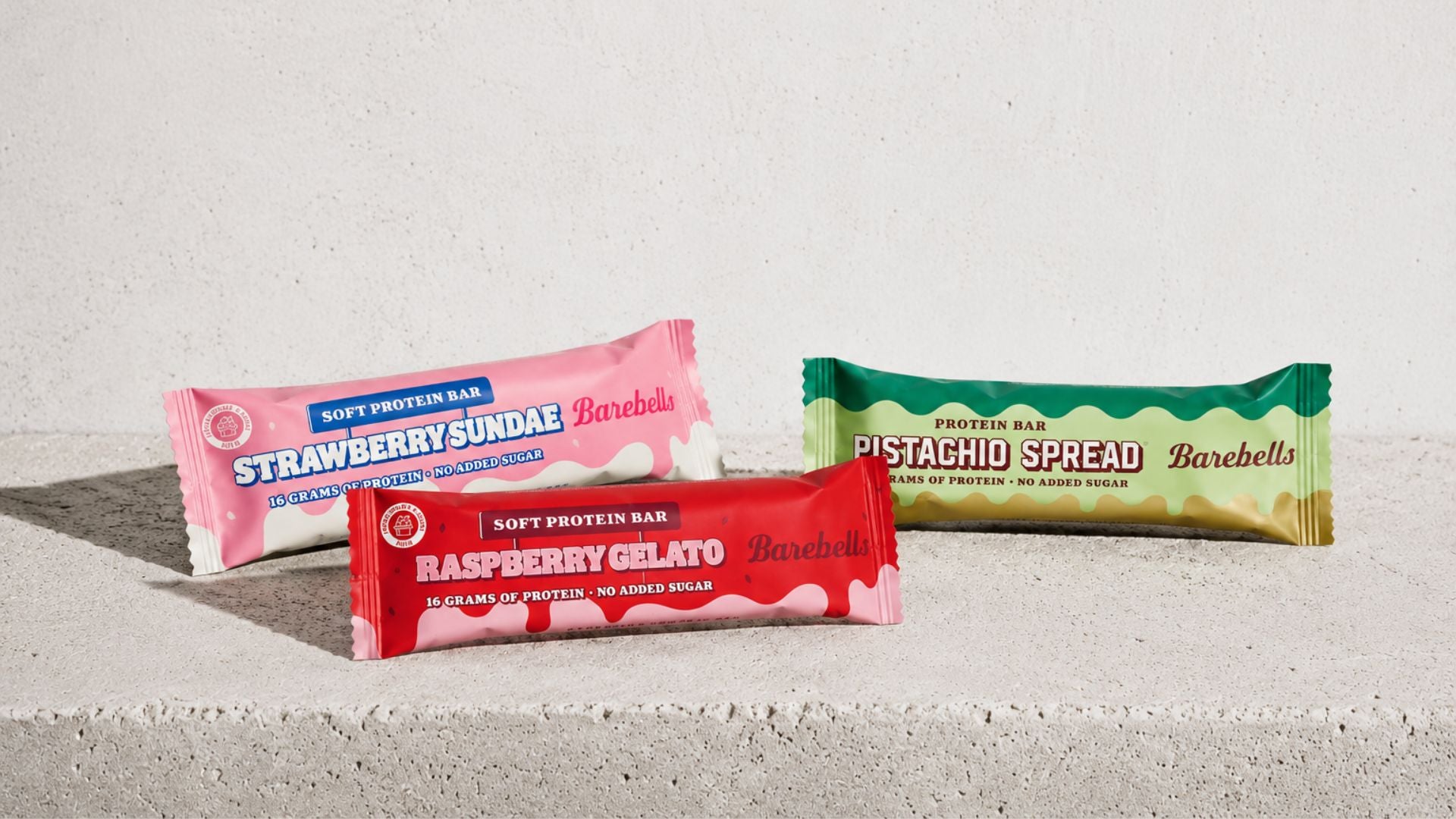 Three protein bars from Barebells on a concrete surface