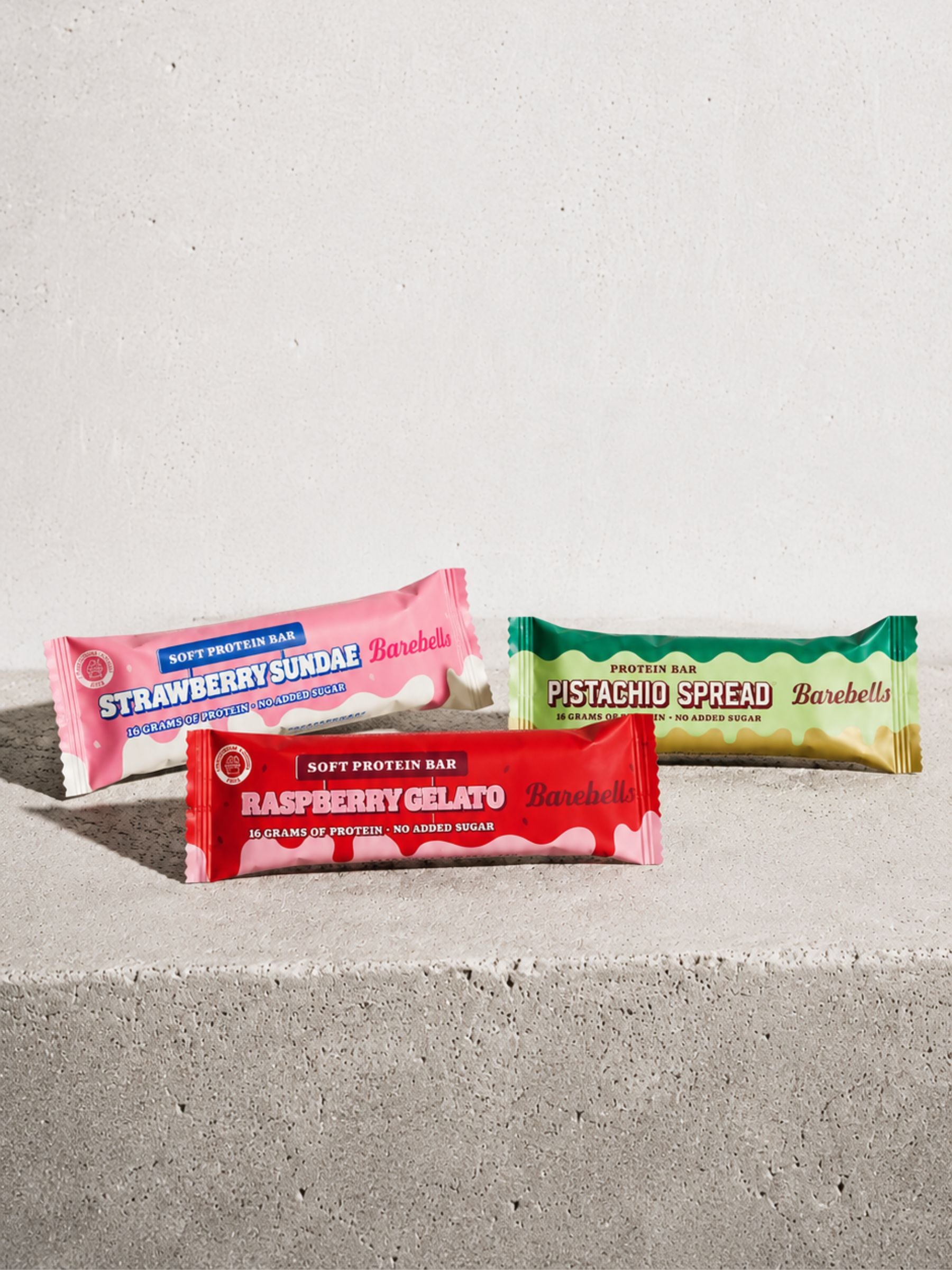 Three protein bars from Barebells on a concrete surface